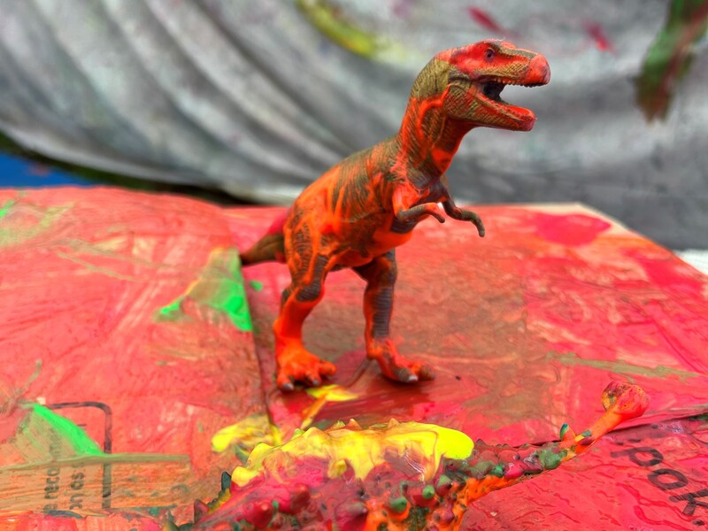 A toy dinosaur covered in paint