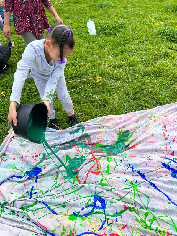 A child pours paint on a sheet