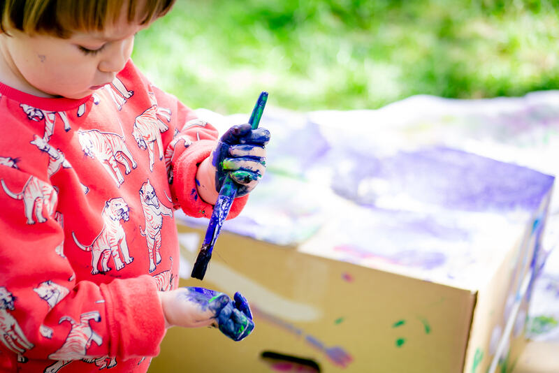 A child paints their hands with blue paint.