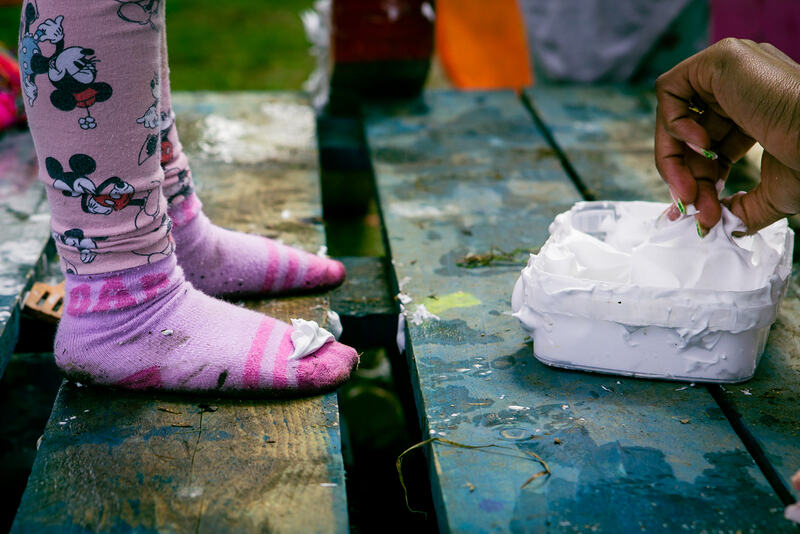A child's shoeless feet next to a tub of shaving foam.