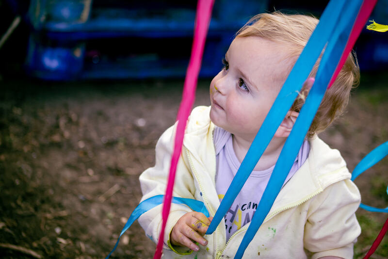 A toddler plays with hanging ribbons.